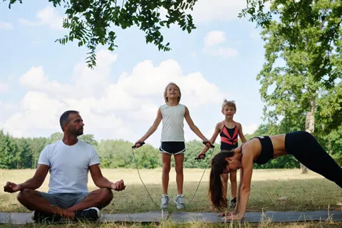 Familia haciendo ejercicio juntos en un parque, simbolizando un estilo de vida cardioprotector y la importancia de la prevención compartida.
